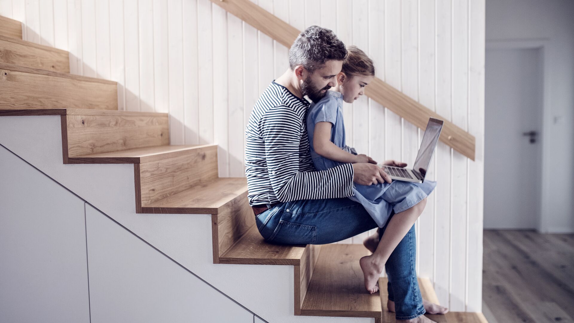 father-and-kid-sitting-on-stairs-using-laptop