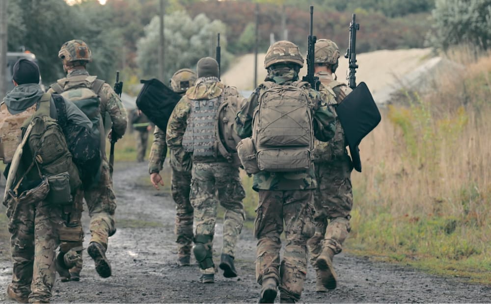 A group of soldiers walking down a dirt road.