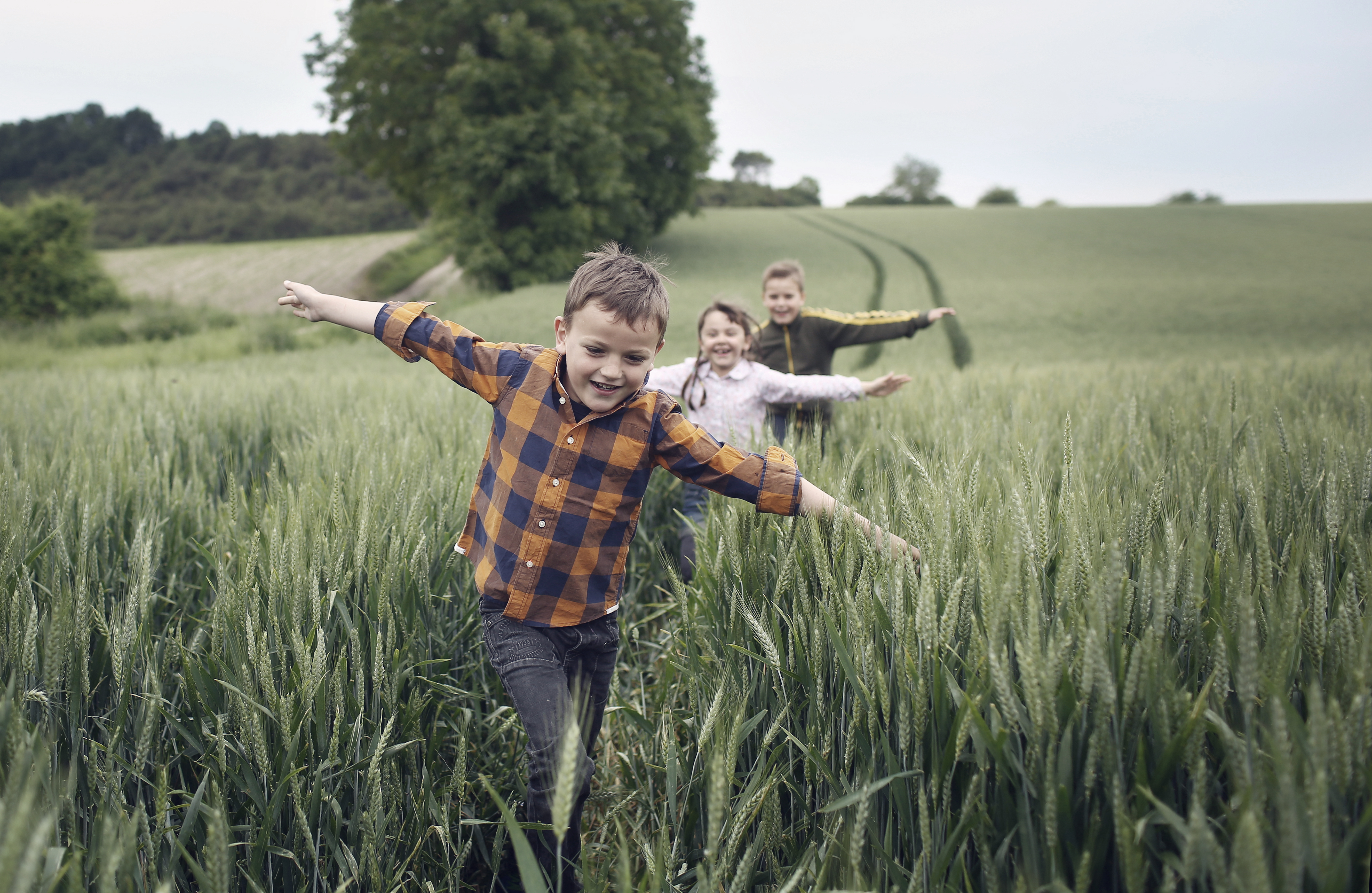 Kolme lasta juoksee pellolla