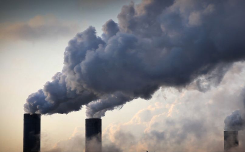 Smoke billows from stacks of industrial smokestacks.