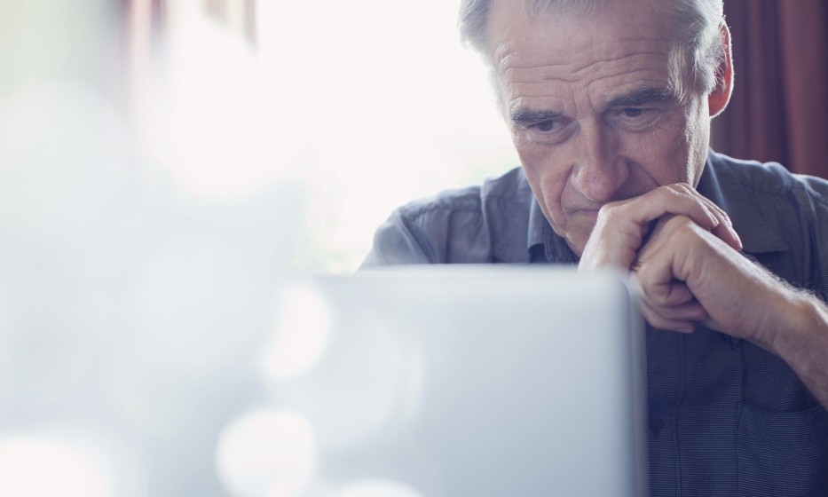 senior-man-with-hands-clasped-using-laptop