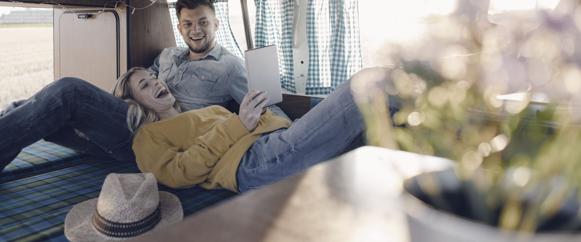 Happy young couple looking at tablet inside camper van